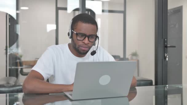 Νεαρός Αφρικανός με ακουστικά Μιλώντας σε απευθείας σύνδεση με τον πελάτη στο τηλεφωνικό κέντρο - Πλάνα, βίντεο