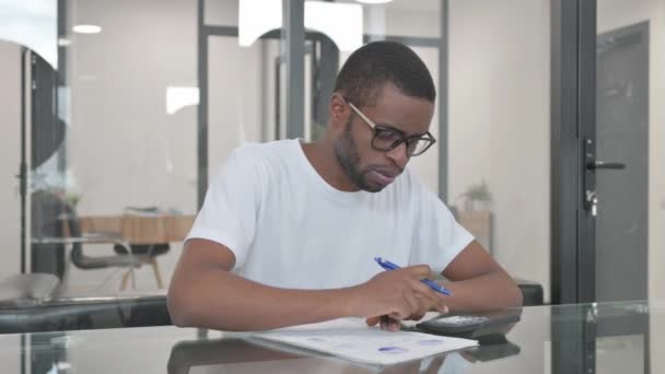 Joven africano trabajando en documentos en la oficina - Metraje, vídeo