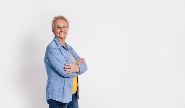 Retrato de velha empresária confiante com braços cruzados sorrindo e de pé sobre fundo branco - Foto, Imagem