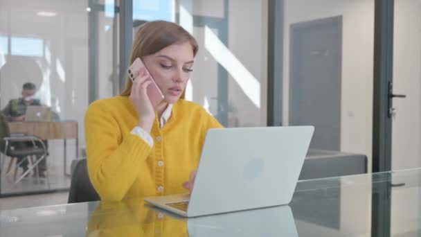 Nuori nainen puhuu puhelimessa töissä - Materiaali, video
