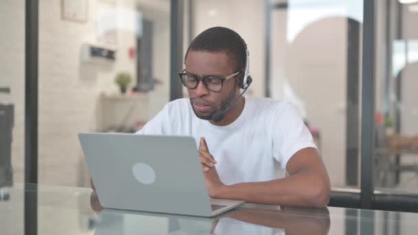 Afrikkalainen amerikkalainen mies kuulokkeiden kanssa puhuu asiakkaan kanssa Call Centerissä - Materiaali, video