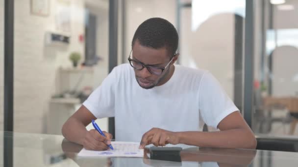 Hombre afroamericano haciendo papeleo y cálculo - Imágenes, Vídeo