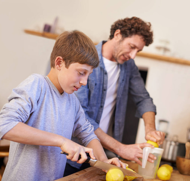 Ojciec, dziecko i owoce cytryny w kuchni dla lemoniady odżywiania na śniadanie drinka, napoju lub dobrego samopoczucia. Mężczyzna, syn i sokowirówka sprzęt w mieszkaniu lub świeże owoce cytrusowe, witaminy c lub jelit zdrowia. - Zdjęcie, obraz