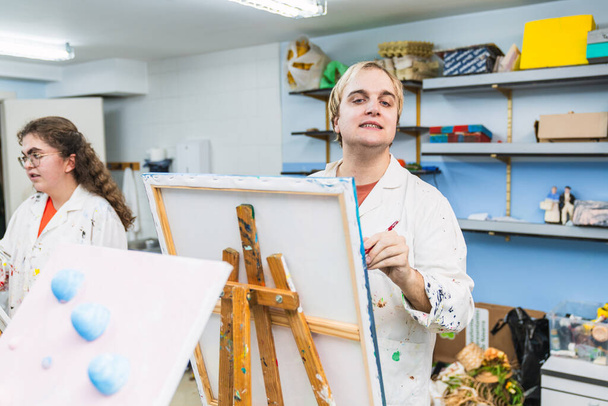 Motivoitunut vammainen taiteilija työskentelee iloisen luokan maalauksen parissa - Valokuva, kuva