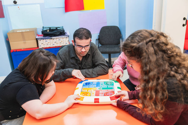 Individuos con una persona con síndrome de Down involucrados en un juego de aprendizaje. - Foto, imagen