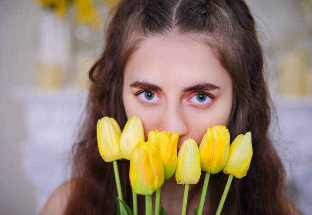 Close-up of a girls eyes with yellow tulips. Spring thoughtful mood. - Photo, Image