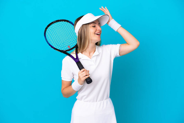 Young tennis player Romanian woman isolated on blue background smiling a lot - Photo, Image