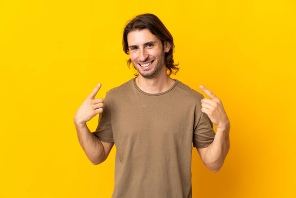 Молодий красивий чоловік ізольований на жовтому тлі, даючи великі пальці вгору жест - Фото, зображення