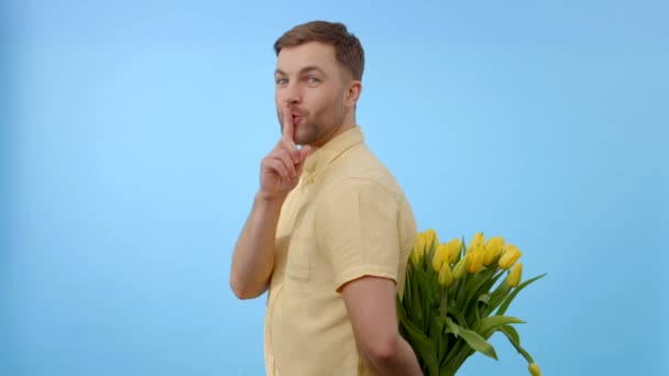 Bir adam elinde büyük bir demet parlak sarı çiçek tutuyor. Çiçekler canlı ve erkek kıyafetlerine karşı kontrastlı. - Video, Çekim