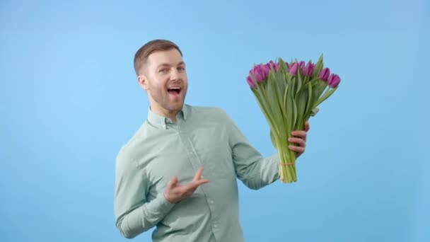 Adamın elinde koyu arkaplanda mor lalelerden oluşan bir buket var. Anneler Günü için bahar çiçekleri, Uluslararası Kadınlar Günü, doğum günü - Video, Çekim