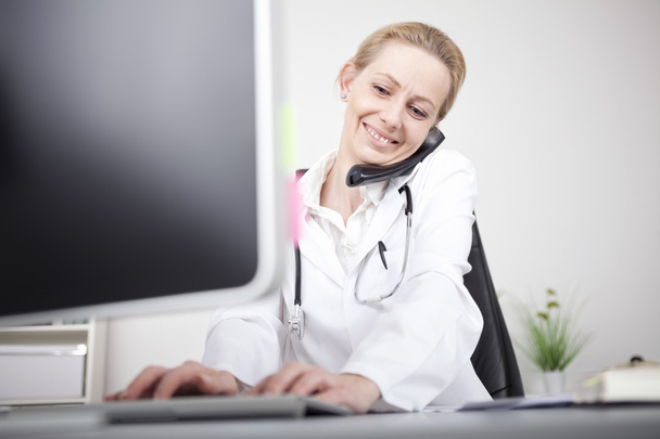 Счастливая женщина врач по телефону с помощью компьютера
 - Фото, изображение