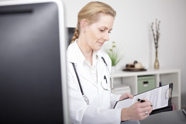 Onnellinen nainen lääkäri kirjoittaa diagnoosi paperille
 - Valokuva, kuva