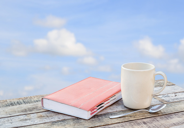 Notebook and coffee cup on wooden table over blurred sky backgro - Foto, Imagem
