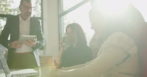 Generációk közötti kreatív emberek részt vesznek egy alkalmi üzleti találkozó egy modern irodai környezetben, megvitatása egy digitális tablet. - Felvétel, videó