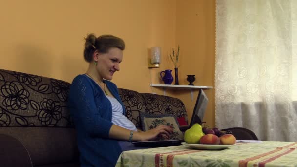 Šťastný těhotná žena pracovat s notebookem a psát tužkou - Záběry, video