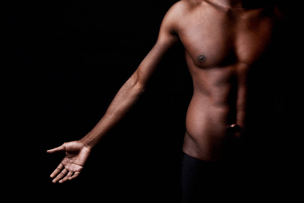 Czarny mężczyzna, ciało i mięśnie z fitness w cieniu do ćwiczeń lub treningu na ciemnym tle studio. Zbliżenie młodego afrykańskiego mężczyzny lub kulturysty z postacią męską lub umięśnioną na makiecie. - Zdjęcie, obraz