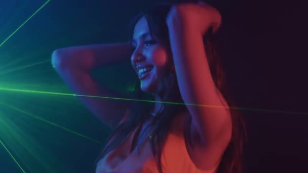 Medium shot van positieve gen Z meisje opknoping out in nachtclub, neon licht en groene laser op de achtergrond - Video