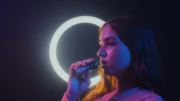 Boční pohled na ženu foukání vape kouř při clubbing v neonu s kruhovým světlem v pozadí - Záběry, video
