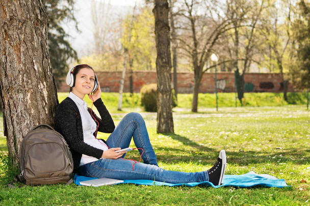 Young girl bent against a tree listening to music - Foto, Bild