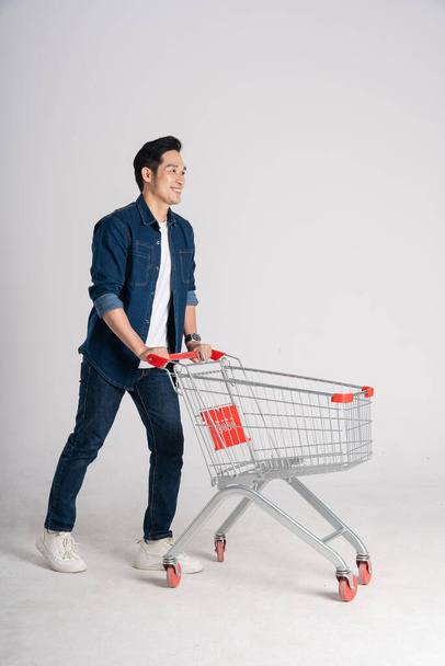 Felice uomo sorridente spingendo carrello supermercato isolato su sfondo bianco - Foto, immagini