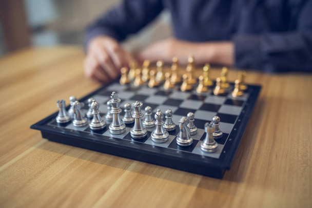 Strategic contemplation in action with a person making a chess move, focus on the golden and silver pieces. Business strategy success concept. - Photo, Image