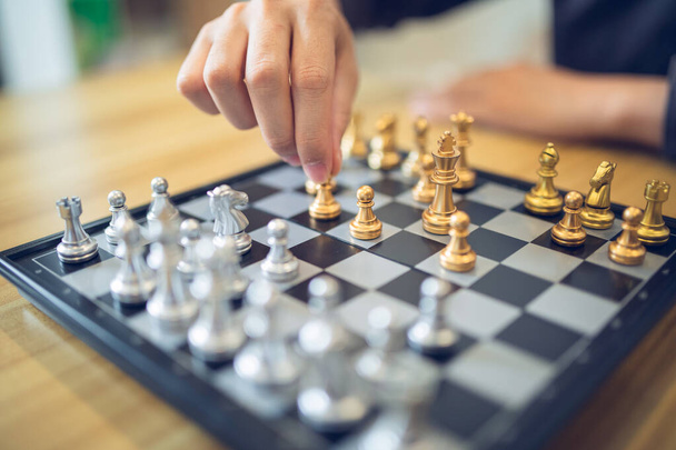 Strategische contemplatie in actie met een persoon die een schaakzet doet, focus op de gouden en zilveren stukken. Succesconcept bedrijfsstrategie. - Foto, afbeelding