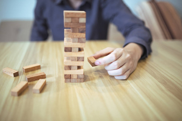 Ellerin tahta blok kule oyunu oynadığı iş stratejisi kavramı risk ve istikrarı sembolize ediyor. Risk yönetimi planlanıyor. - Fotoğraf, Görsel