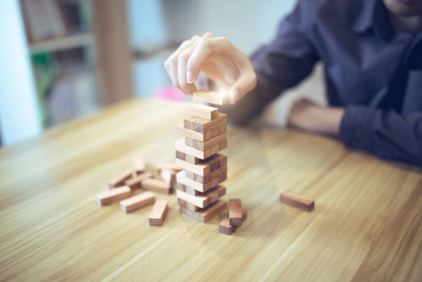 Επιχειρηματική στρατηγική έννοια με τα χέρια παίζει ένα ξύλινο παιχνίδι πύργος μπλοκ, συμβολίζοντας τον κίνδυνο και τη σταθερότητα. Διαχείριση κινδύνων σχεδιασμού. - Φωτογραφία, εικόνα