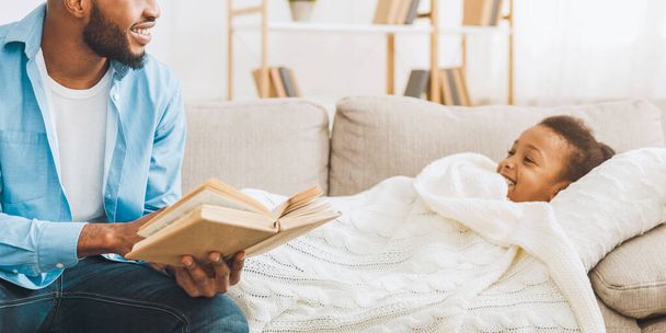 Huolehtiva isä lukee tarinoita pienelle tyttärelle ennen nukkumaanmenoa kotona, tyhjä tila
 - Valokuva, kuva