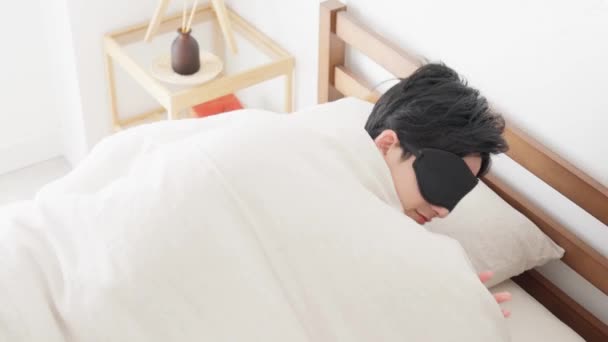 Een man slaapt met een oogmasker in een heldere kamer. - Video