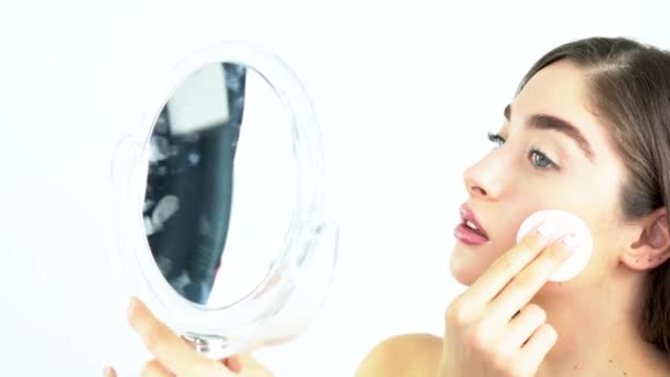Mooie blonde vrouw met spiegel verwijderen van make-up van haar gezicht. - Video