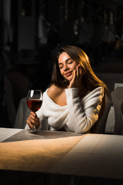 ワインのグラスを持っている若い女性.レストランでワインを飲む女性.赤ワインのコンセプト - 写真・画像