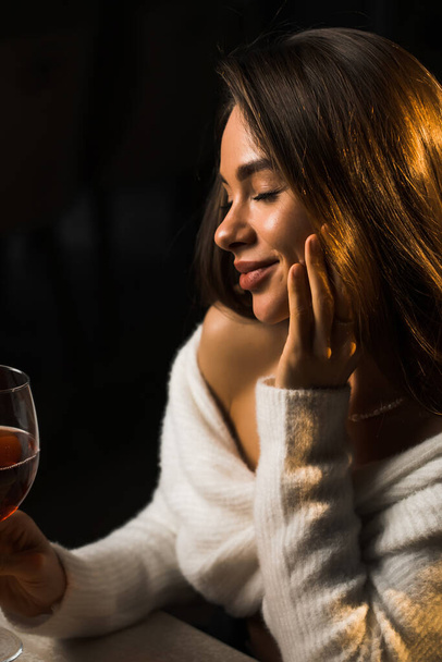 Νεαρή γυναίκα κρατώντας ένα ποτήρι κρασί.Γυναίκα πίνοντας κρασί σε ένα εστιατόριο.Κόκκινο κρασί έννοια - Φωτογραφία, εικόνα