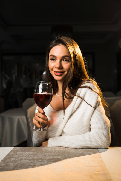 Nuori nainen, jolla on lasillinen viiniä.Nainen, joka juo viiniä ravintolassa.Punaviini käsite - Valokuva, kuva