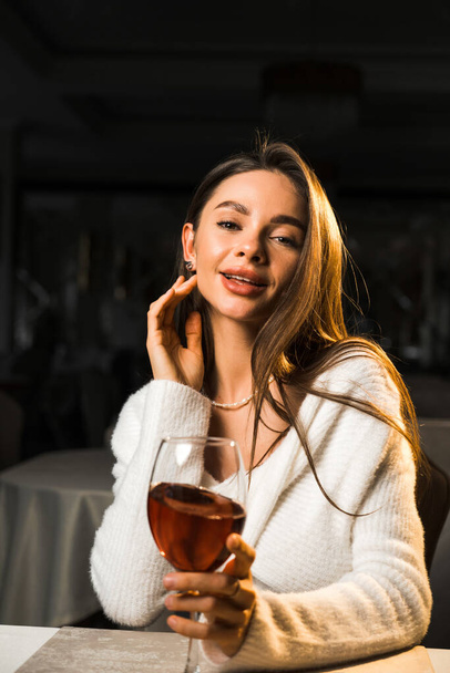 Mujer joven sosteniendo una copa de vino.Mujer bebiendo vino en un restaurante.Concepto de vino tinto - Foto, Imagen
