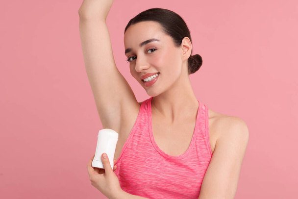 Beautiful woman applying deodorant on pink background - Foto, imagen