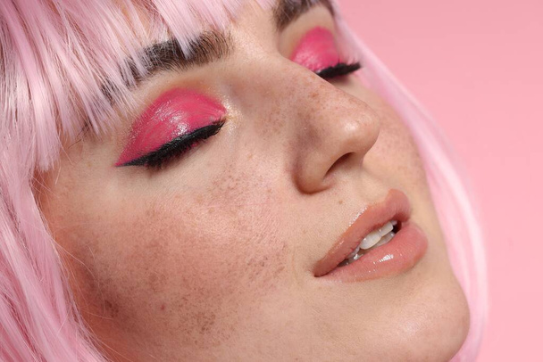 Beautiful woman with bright makeup and fake freckles on pink background, closeup - Fotó, kép