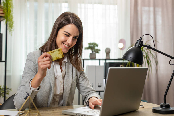 Happy Caucasian liiketoiminnan nainen käyttää pankkikortti ja kannettava tietokone online-ostoksia maksuja kotona toimistossa. Liiketoimi. Hymyilevä tyttö freelancer osto tietokoneella E-pankki sovellus palvelu - Valokuva, kuva