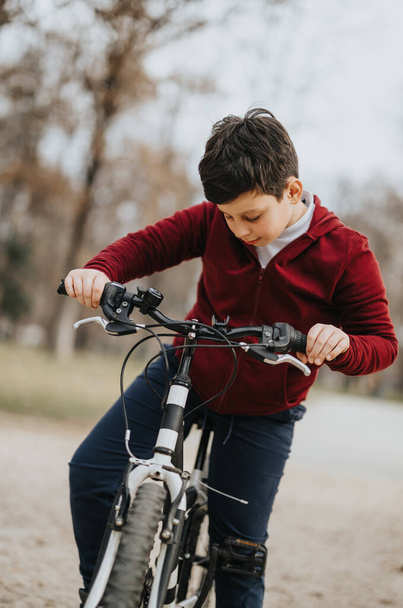 Um menino experimenta a felicidade e a liberdade de andar de bicicleta ao ar livre em um parque da cidade cercado por vegetação. - Foto, Imagem