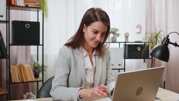 Happy businesswoman freelancer taking break leaning on chair after working celebrating success victory at modern home office workplace desk. Girl in formal suit puts hands behind head relaxing at home - Footage, Video