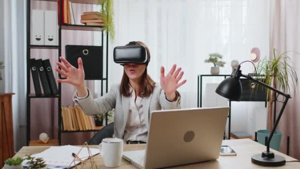 Excited young businesswoman using virtual reality futuristic technology VR app headset to simulation 3D 360 video at modern home office desk. Female manager freelancer scrolling gesturing online work. - Footage, Video