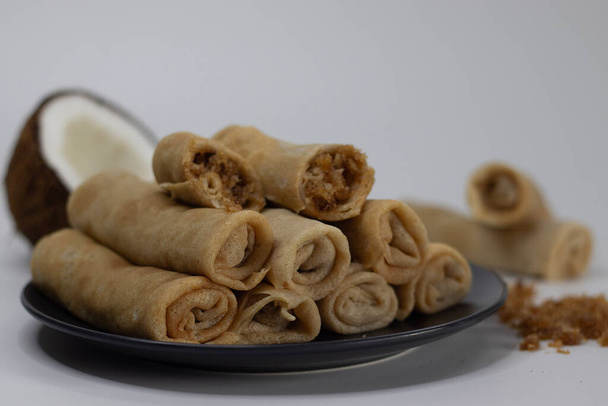 Coconut jaggery crepes. South Indian cuisine, sweet dessert, perfect for foodies and culinary enthusiasts. Pancake made of wheat flour, egg and milk, rolled with coconut jaggery mix in the center - Photo, Image