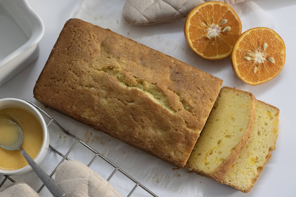 Sliced Loaf of Orange pound cake, ook bekend als citrus brood taart of sinaasappelboter taart. Vochtige, smaakvolle dessert, met pittige glazuur perfect voor liefhebbers van eten, bakken liefhebbers, en voor zoete hunkering - Foto, afbeelding