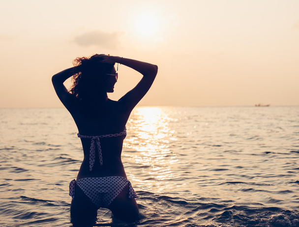 Frau genießt Freiheit und fühlt sich am Strand bei Sonnenuntergang wohl - Foto, Bild
