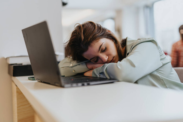 Drenada de un duro día de trabajo, la empleada se encuentra dormida en el escritorio, una escapada temporal de los desafíos de los días. - Foto, imagen