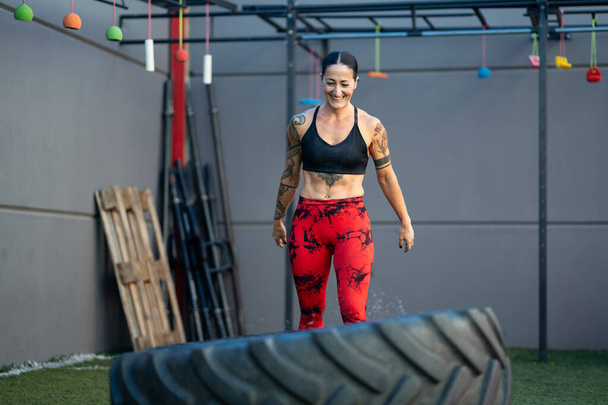 Szczęśliwa silna kobieta dumna podczas treningu na siłowni za pomocą koła - Zdjęcie, obraz
