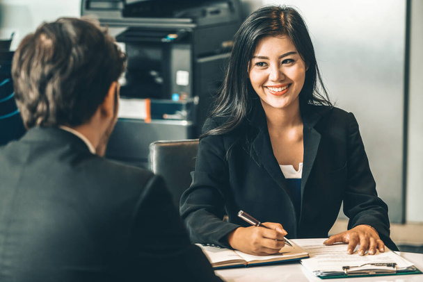 Businesswoman from human resources department is interviewing businessman candidate for job application in meeting room while considering his CV resume document. Employee hiring business concept. uds - Photo, Image