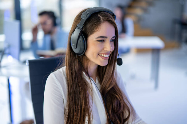 Closeup headshot of smiling young female customer support agent with headset at call center - Photo, Image