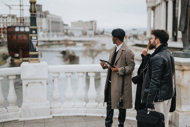 Jóvenes socios comerciales que trabajan de forma remota al aire libre con una tableta conectada digitalmente en un paisaje urbano, simbolizando el espíritu empresarial moderno. - Foto, imagen