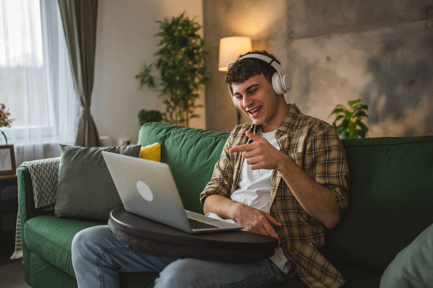 Egy kaukázusi tinédzser férfi laptopot használ, otthon videohívása van. - Fotó, kép
